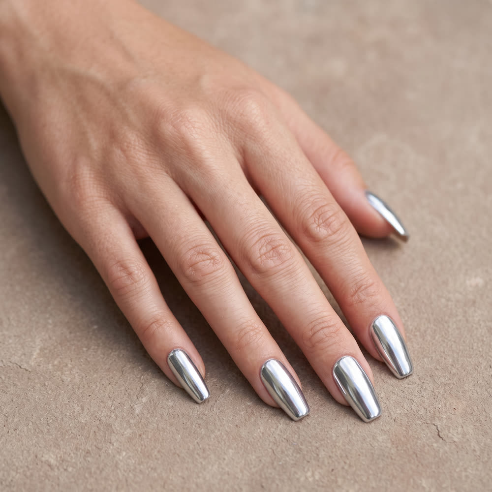 A hand on warm stone with mirror-finish chrome silver nails